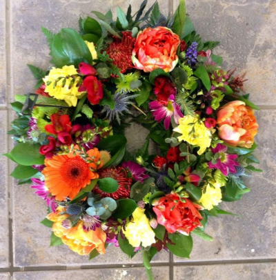 Vibrant Open Styled Funeral Wreath - The vibrant open wreath is available in three sizes, 12", 14" and 16"  Made to order with a vibrant and colourful combination of oranges, lemons, and deep reds. Flowers may vary according to the season. This is our best-selling funeral piece suitable for a man or a lady and it will always be made with skill and care by Molly Blooms..

Supplied with a suitable card and a handwritten message, this piece can be delivered to the funeral home or to a private address of your choosing.